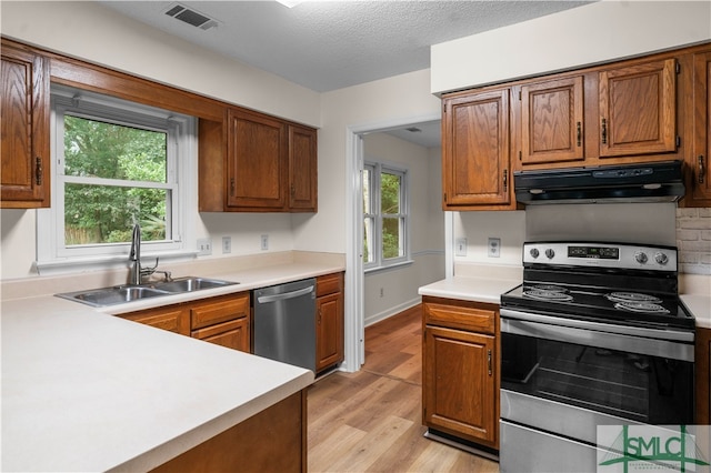 kitchen featuring a textured ceiling, light hardwood / wood-style flooring, sink, and appliances with stainless steel finishes