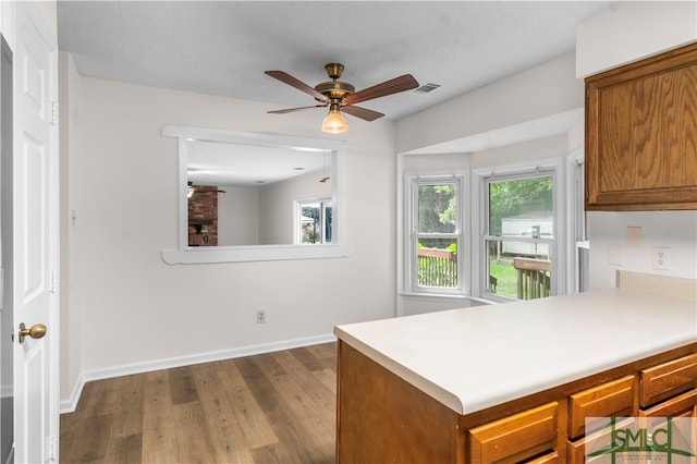 kitchen featuring a textured ceiling, ceiling fan, wood-type flooring, and kitchen peninsula