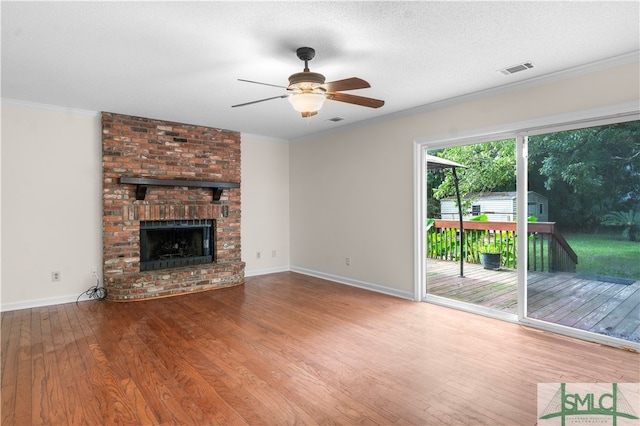 unfurnished living room featuring crown molding, ceiling fan, hardwood / wood-style floors, and a brick fireplace