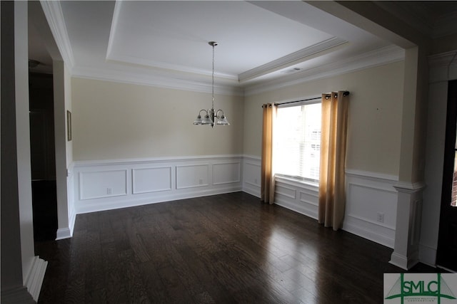 spare room with a tray ceiling, dark wood-type flooring, ornamental molding, and a chandelier