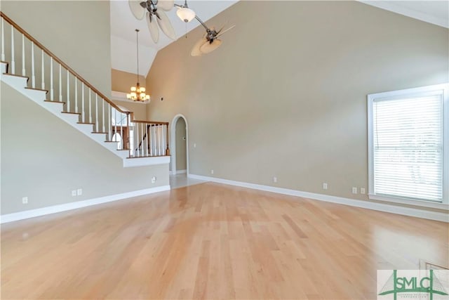 unfurnished living room with lofted ceiling, ceiling fan with notable chandelier, and light wood-type flooring