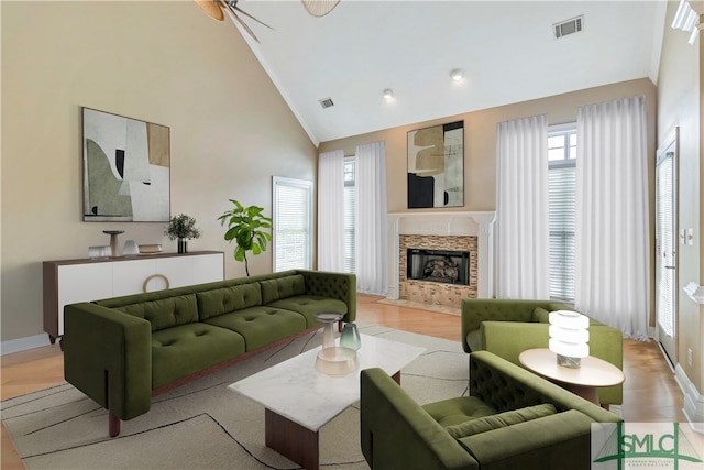 living room with a fireplace, light hardwood / wood-style floors, high vaulted ceiling, and ceiling fan