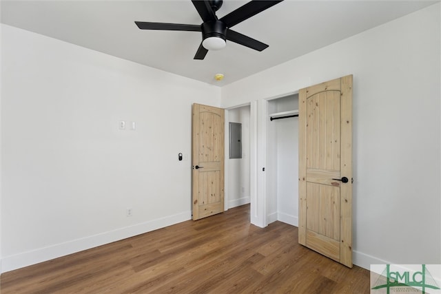 unfurnished bedroom with wood-type flooring, electric panel, ceiling fan, and a closet