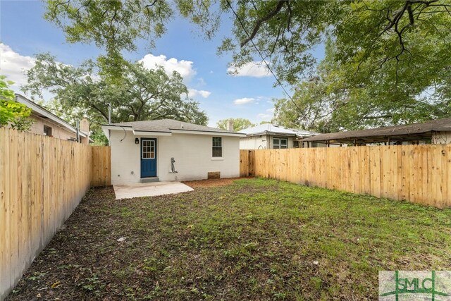 back of house with a lawn and a patio area