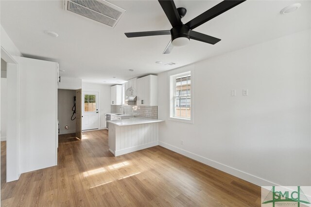 kitchen with white cabinetry, kitchen peninsula, sink, ceiling fan, and light hardwood / wood-style floors