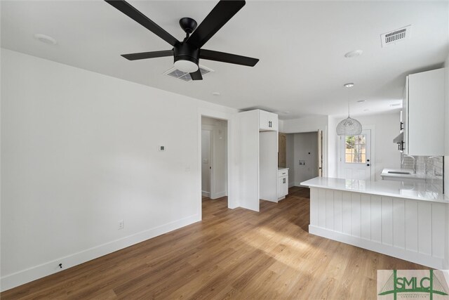 kitchen with light wood-type flooring, white cabinetry, ceiling fan, and hanging light fixtures