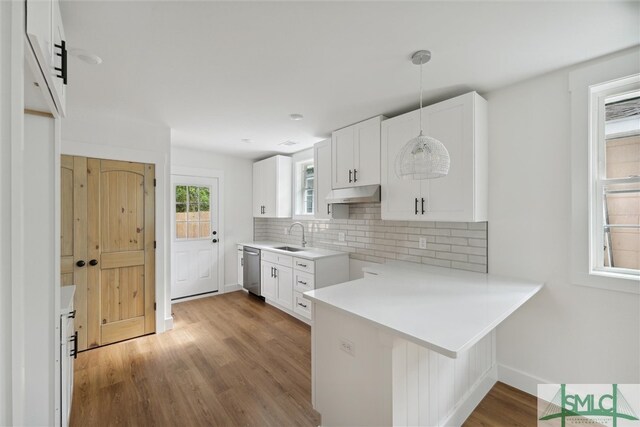 kitchen with hanging light fixtures, kitchen peninsula, light wood-type flooring, and white cabinets