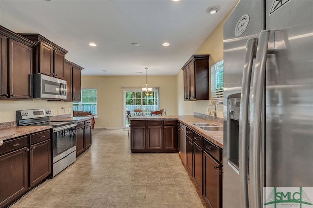 kitchen featuring hanging light fixtures, stainless steel appliances, sink, kitchen peninsula, and dark brown cabinetry