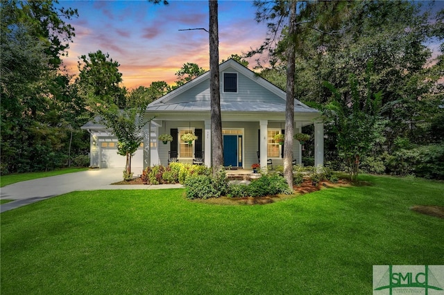 view of front of property with a porch, a garage, and a lawn