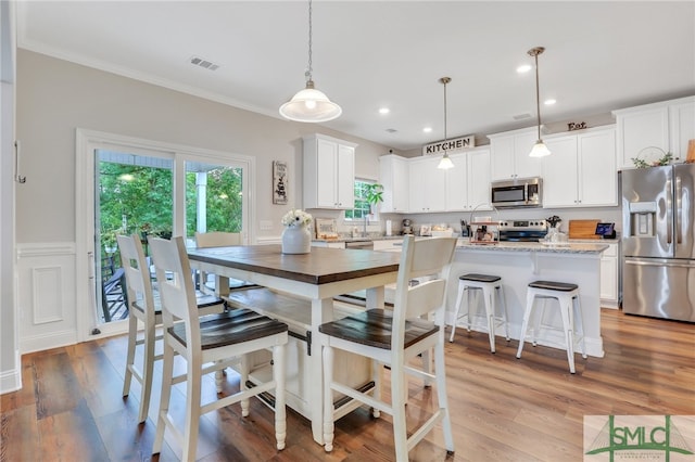 dining room with ornamental molding and light hardwood / wood-style flooring