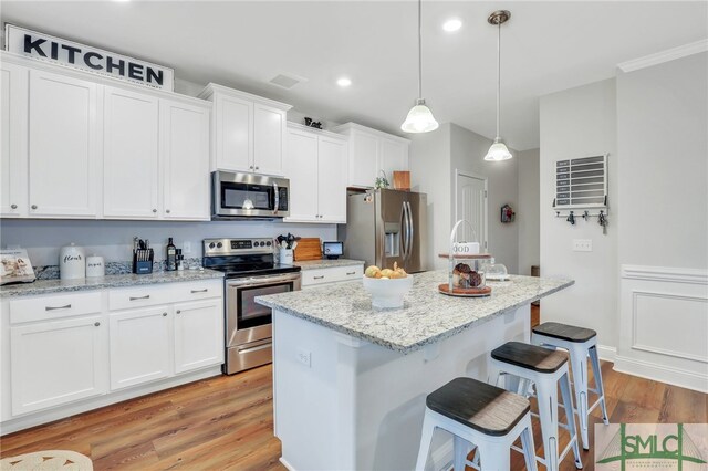 kitchen featuring appliances with stainless steel finishes, white cabinetry, a kitchen island, and pendant lighting