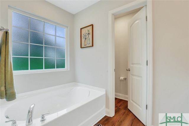 bathroom with a tub to relax in and hardwood / wood-style flooring