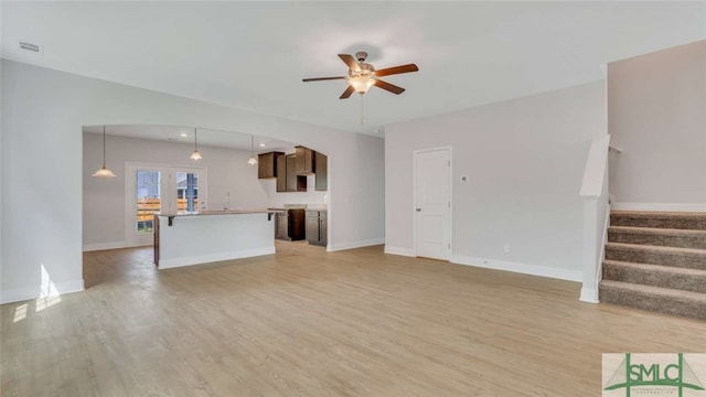 unfurnished living room featuring light wood-type flooring, ceiling fan, and sink