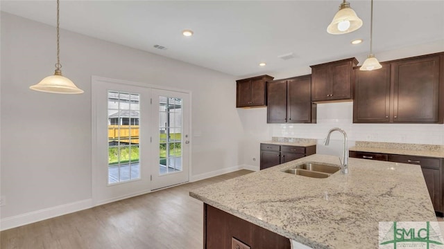 kitchen featuring light wood-type flooring, pendant lighting, sink, and light stone countertops