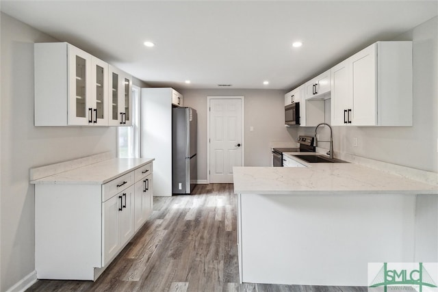 kitchen featuring white cabinetry, stainless steel appliances, kitchen peninsula, sink, and hardwood / wood-style flooring