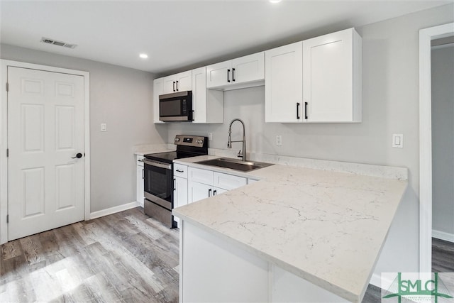 kitchen with white cabinetry, light stone counters, sink, appliances with stainless steel finishes, and light hardwood / wood-style floors