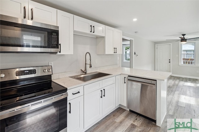 kitchen featuring kitchen peninsula, sink, ceiling fan, appliances with stainless steel finishes, and white cabinets