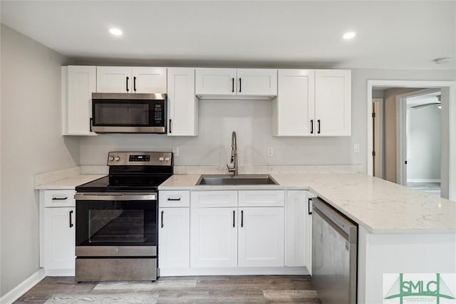 kitchen featuring light wood-type flooring, sink, appliances with stainless steel finishes, and white cabinetry