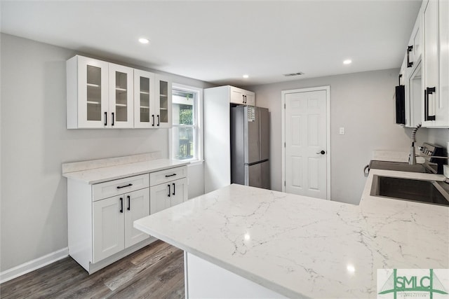 kitchen featuring white cabinets, light stone countertops, stainless steel refrigerator, dark hardwood / wood-style floors, and kitchen peninsula