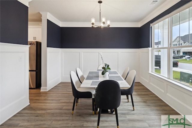 dining area with ornamental molding, a chandelier, and hardwood / wood-style flooring