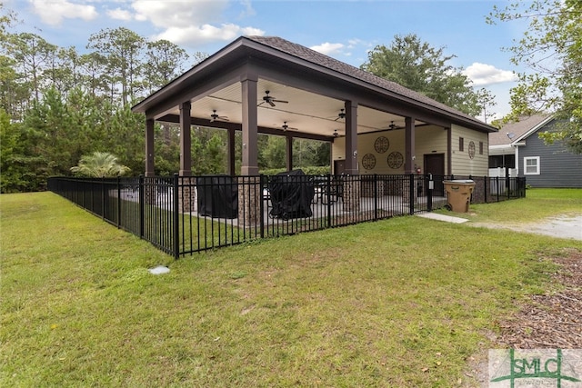 rear view of property featuring ceiling fan and a lawn