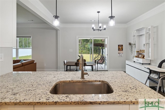 kitchen featuring pendant lighting, crown molding, sink, and a wealth of natural light