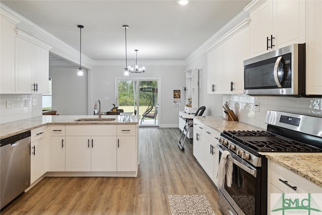 kitchen featuring pendant lighting, light wood-type flooring, sink, white cabinetry, and appliances with stainless steel finishes