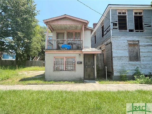 rear view of property featuring a balcony and a lawn