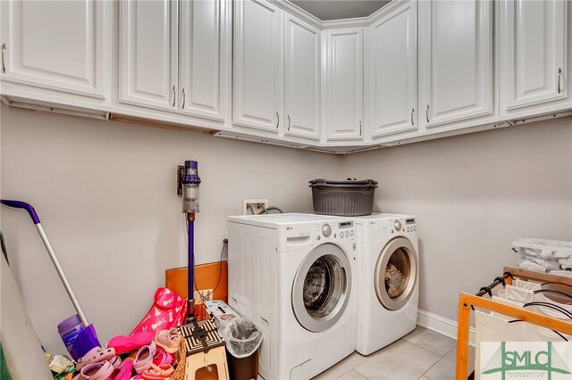 washroom featuring light tile patterned floors, washing machine and clothes dryer, and cabinets