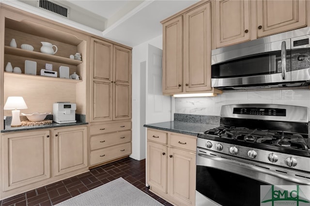 kitchen featuring tasteful backsplash, light brown cabinets, dark stone counters, and appliances with stainless steel finishes