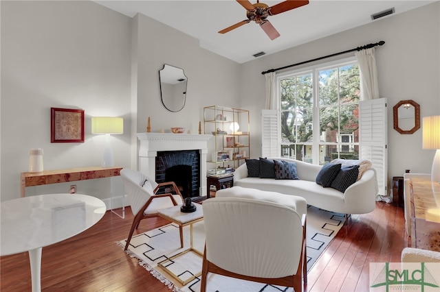 living room featuring ceiling fan, a fireplace, and dark hardwood / wood-style floors