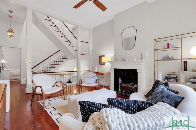 living room with a high ceiling, ceiling fan, and dark wood-type flooring