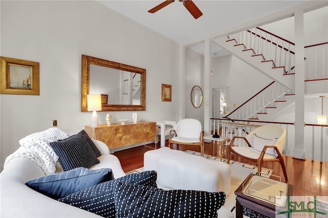 sitting room featuring ceiling fan, wood-type flooring, and a high ceiling