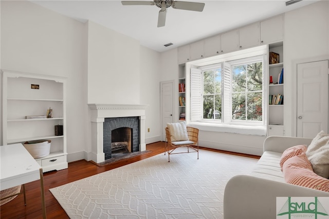 living room with ceiling fan, a fireplace, and wood-type flooring