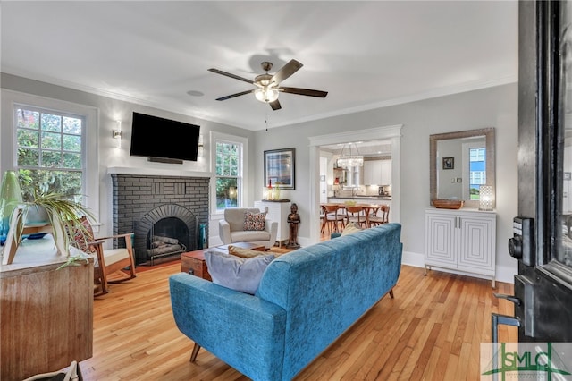 living room featuring light wood-type flooring, ceiling fan, plenty of natural light, and a brick fireplace