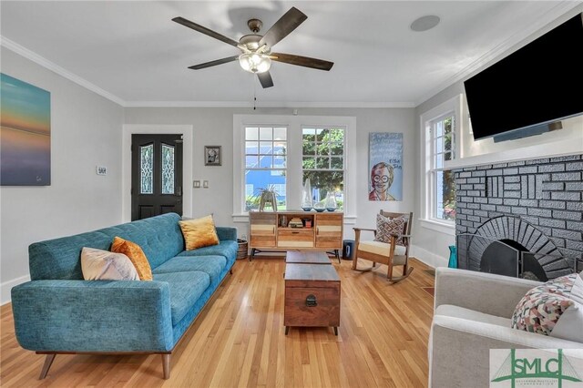 living room featuring a fireplace, crown molding, ceiling fan, and light hardwood / wood-style floors