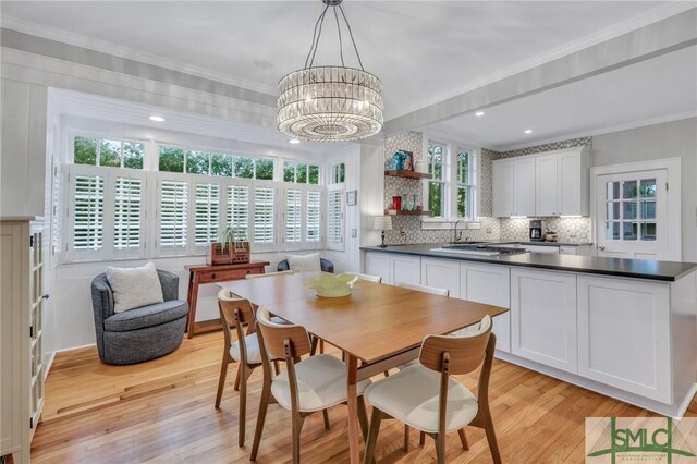 dining area featuring ornamental molding, an inviting chandelier, and light hardwood / wood-style floors