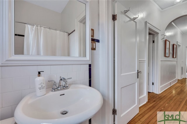 bathroom with curtained shower, wood-type flooring, crown molding, and sink