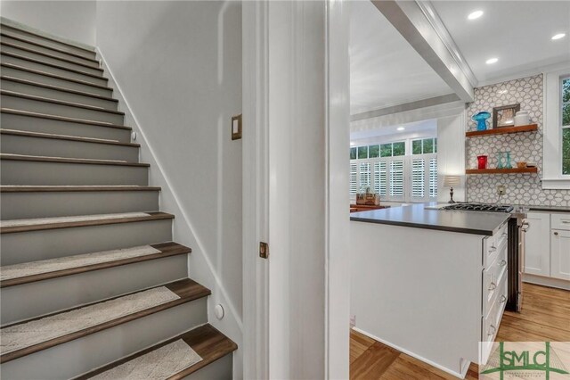 stairs featuring ornamental molding and wood-type flooring