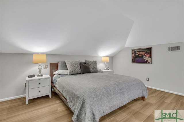 bedroom with vaulted ceiling and light hardwood / wood-style flooring