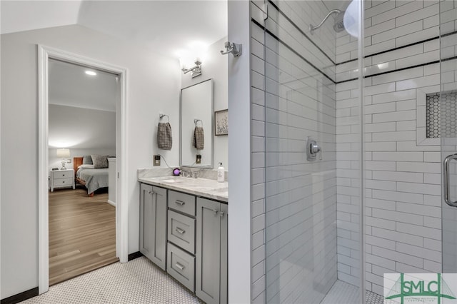 bathroom with vaulted ceiling, hardwood / wood-style flooring, walk in shower, and vanity