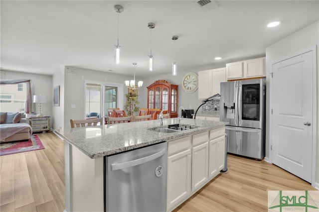 kitchen with white cabinets, a center island with sink, sink, appliances with stainless steel finishes, and a chandelier