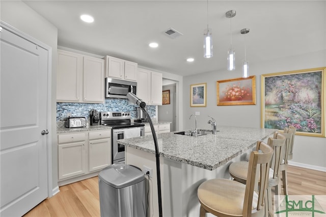 kitchen featuring light stone countertops, hanging light fixtures, white cabinets, and stainless steel appliances