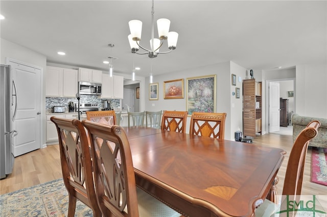 dining space featuring light wood-type flooring and an inviting chandelier