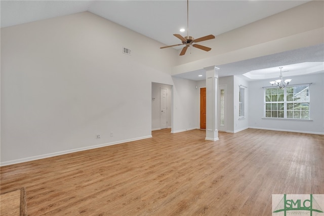 unfurnished living room featuring light wood-type flooring, ornate columns, ceiling fan with notable chandelier, and vaulted ceiling