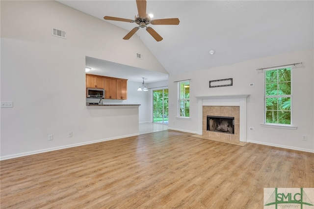 unfurnished living room featuring a fireplace, high vaulted ceiling, ceiling fan, and light hardwood / wood-style floors