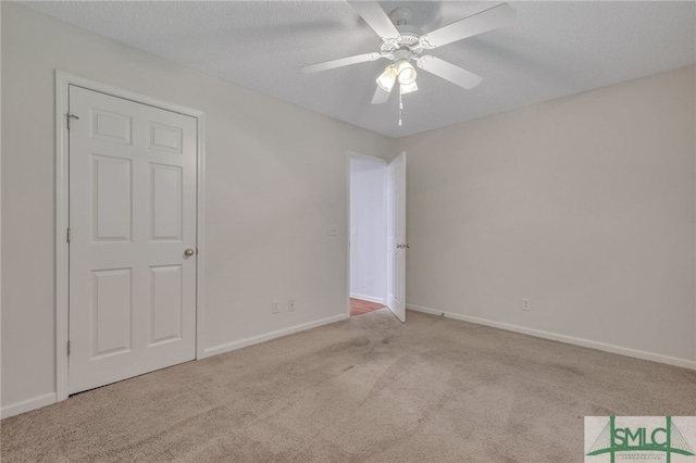 unfurnished bedroom featuring ceiling fan, light carpet, and a textured ceiling