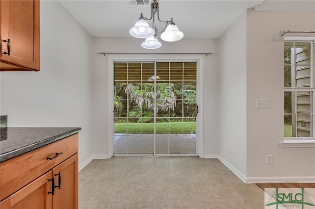 unfurnished dining area featuring a textured ceiling and an inviting chandelier