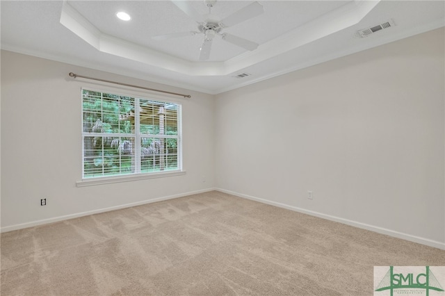 unfurnished room featuring ceiling fan, light colored carpet, a raised ceiling, and ornamental molding