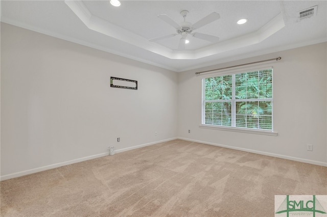 carpeted empty room featuring ceiling fan, a raised ceiling, and ornamental molding